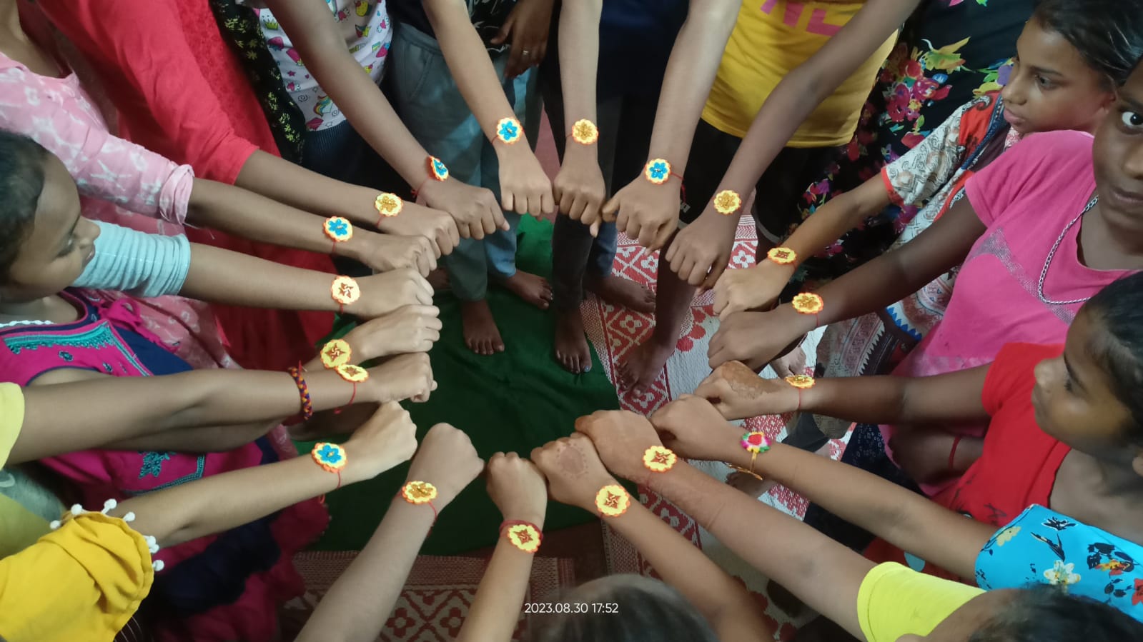 Children and adolescents standing in a circle with handmade wristbands