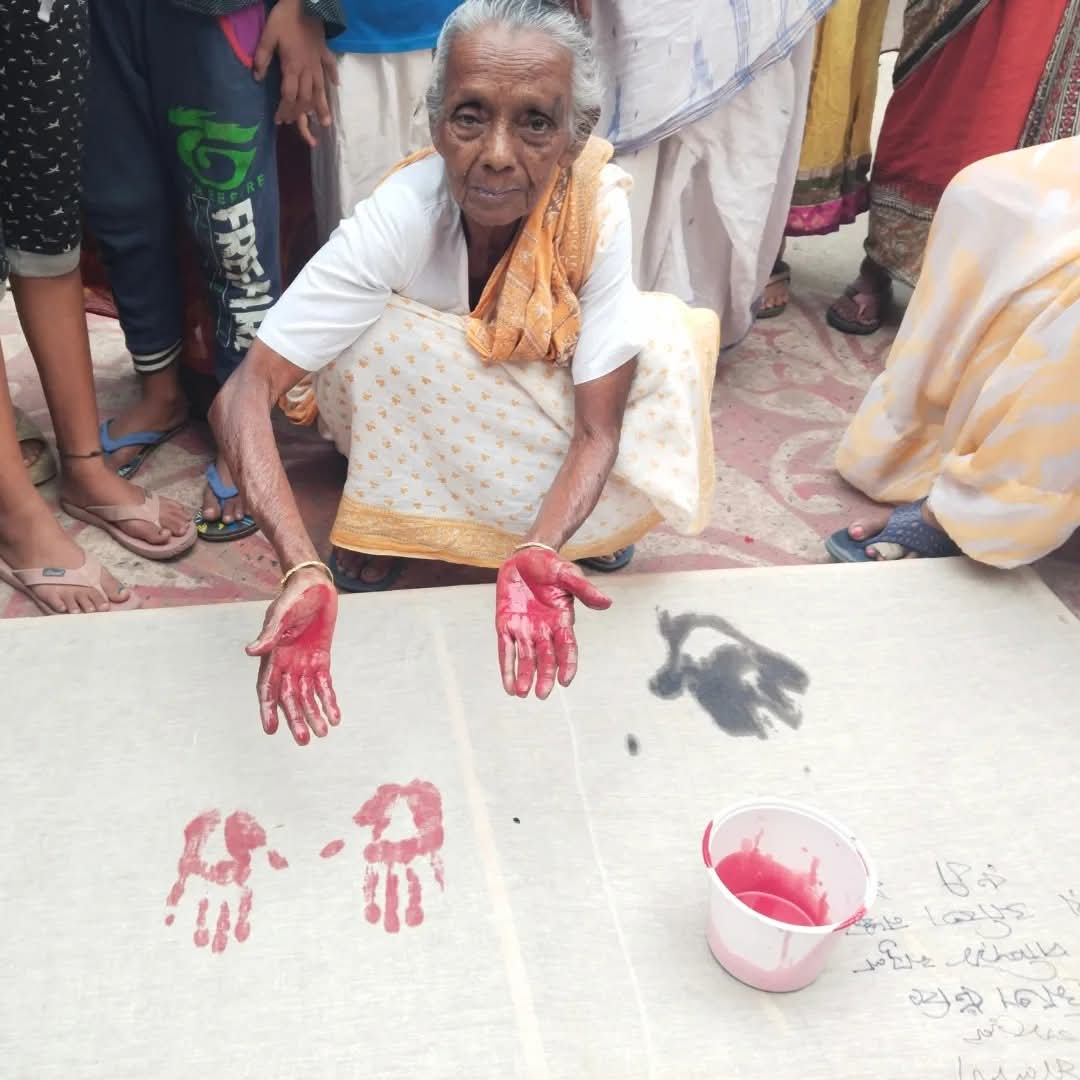 Two women, one elderly, hold a small plant together.