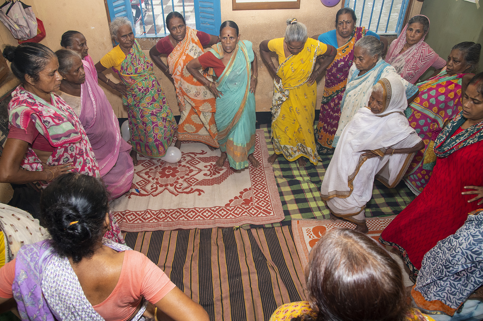 Two women, one elderly, hold a small plant together.